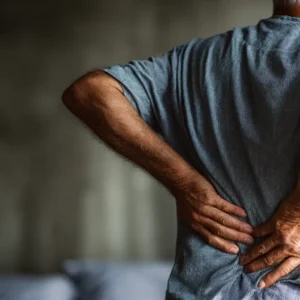 An elderly man holding his lower back in pain, indicating she needs stem cell treatment for her lower back