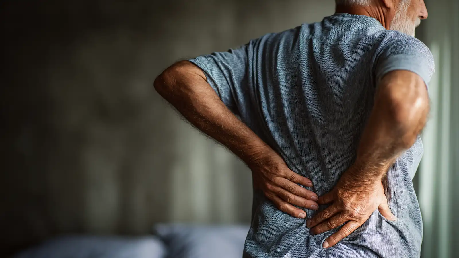 An elderly man holding his lower back in pain, indicating she needs stem cell treatment for her lower back