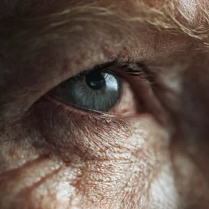 Close-up profile of an elderly woman with glasses, highlighting detailed wrinkles and facial texture, who's suffering from macular degeneration challenges