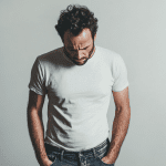 Sad man looking down at his trousers, symbolizing struggles with erectile dysfunction, exploring the effectiveness of stem cell therapy as a potential solution.