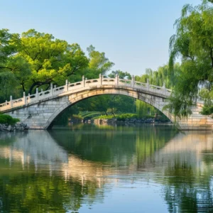 Anji Bridge (Zhaozhou Bridge) in Hebei, China, an ancient stone arch bridge surrounded by lush green trees, reflecting over calm river water on a clear sunny day