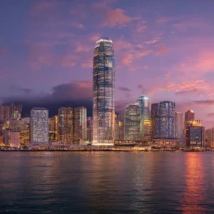 Victoria Harbour skyline in Hong Kong at sunset, featuring the IFC Tower, Bank of China Tower, and illuminated skyscrapers reflecting on the water