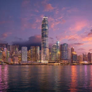 Victoria Harbour skyline in Hong Kong at sunset, featuring the IFC Tower, Bank of China Tower, and illuminated skyscrapers reflecting on the water